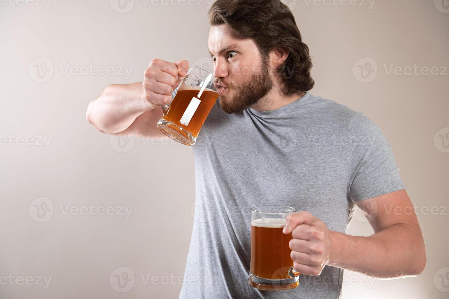 Attractive bearded young man drinking beer from a big mug, side view of his face photo
