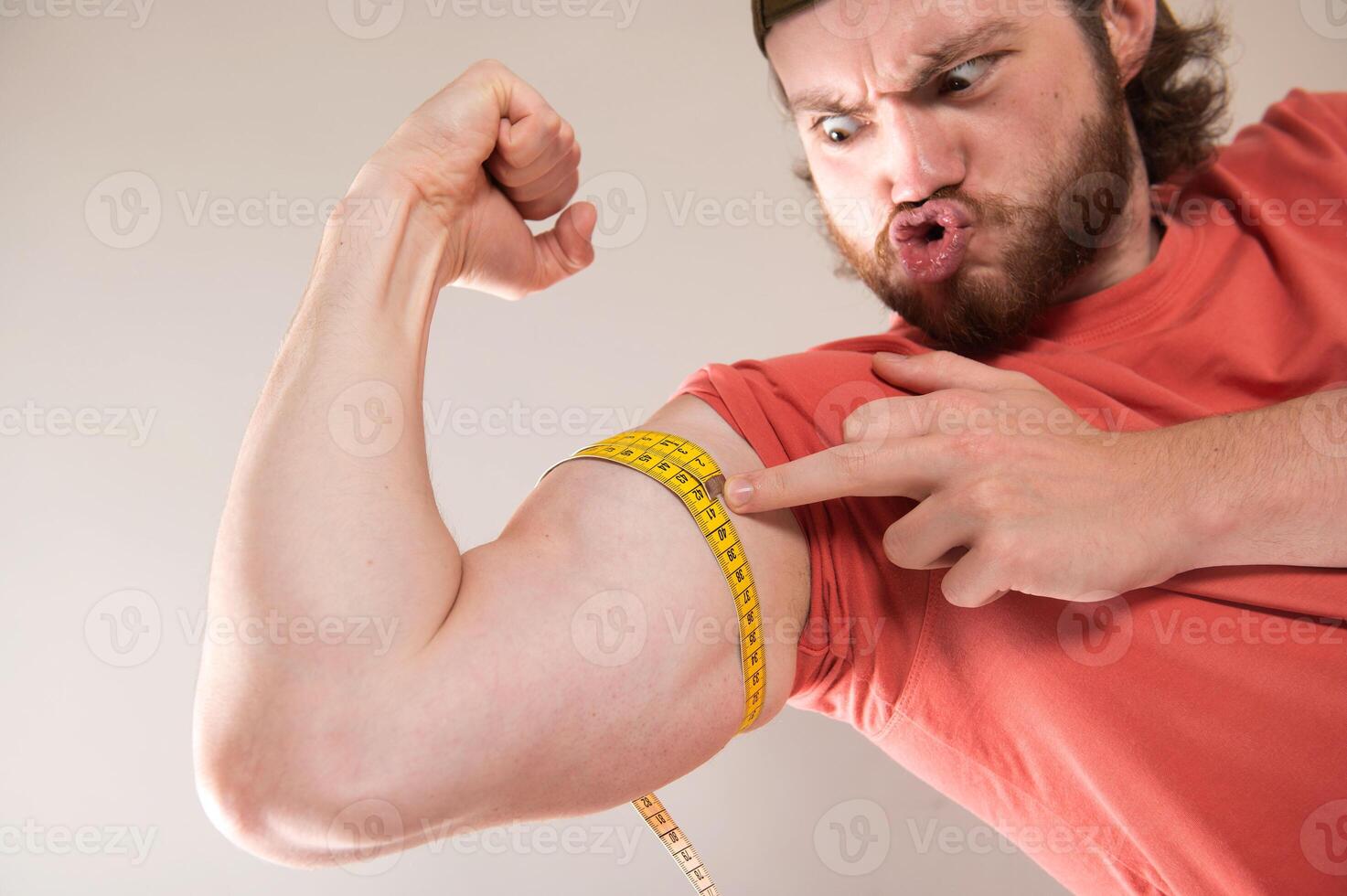 Excited young man measuring his strong arm muscle with tape measure, concept of training and healthy lifestyle photo