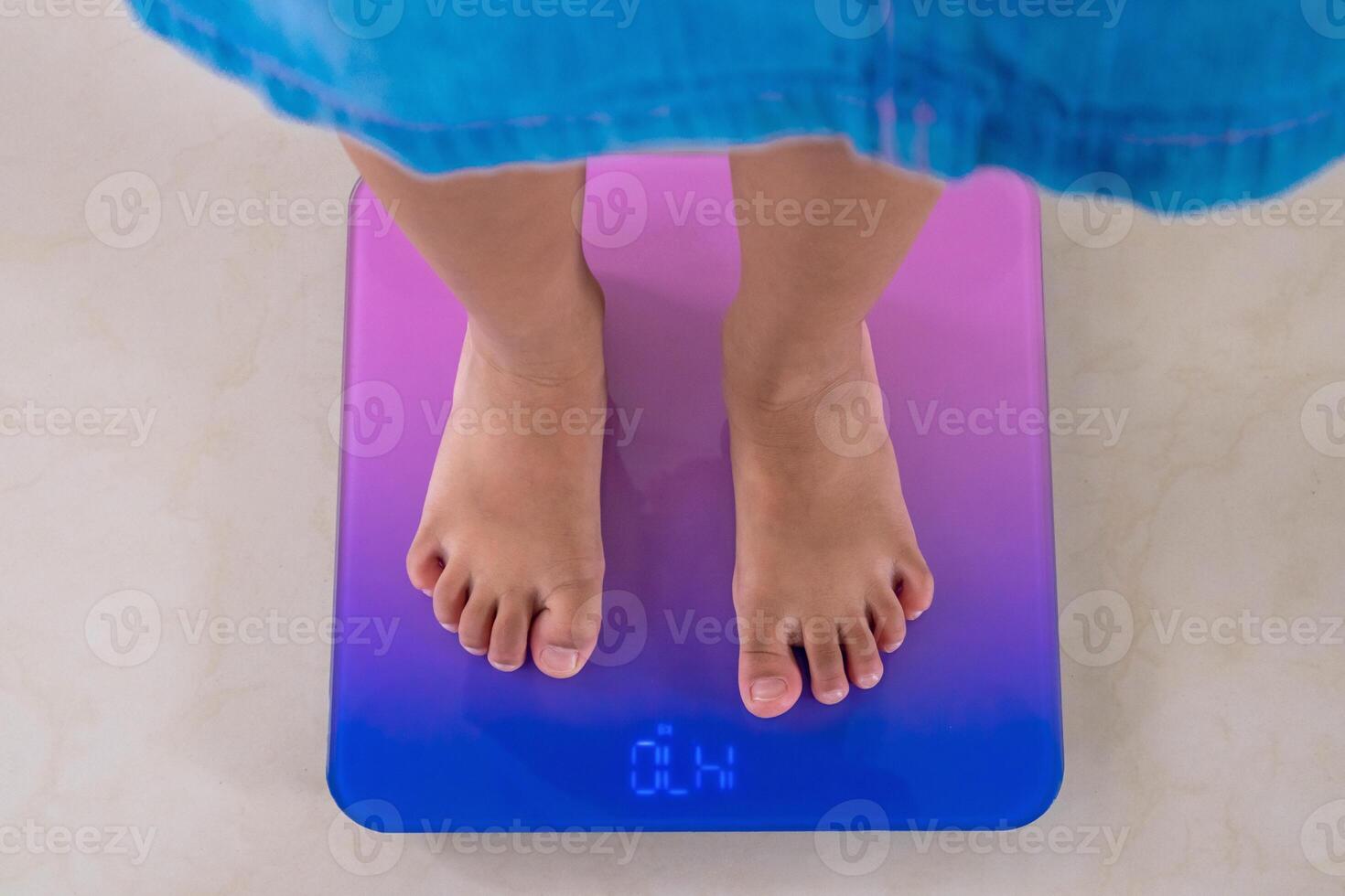 Top view of a little girl feet standing on a digital floor scale. Body weight control concept. photo
