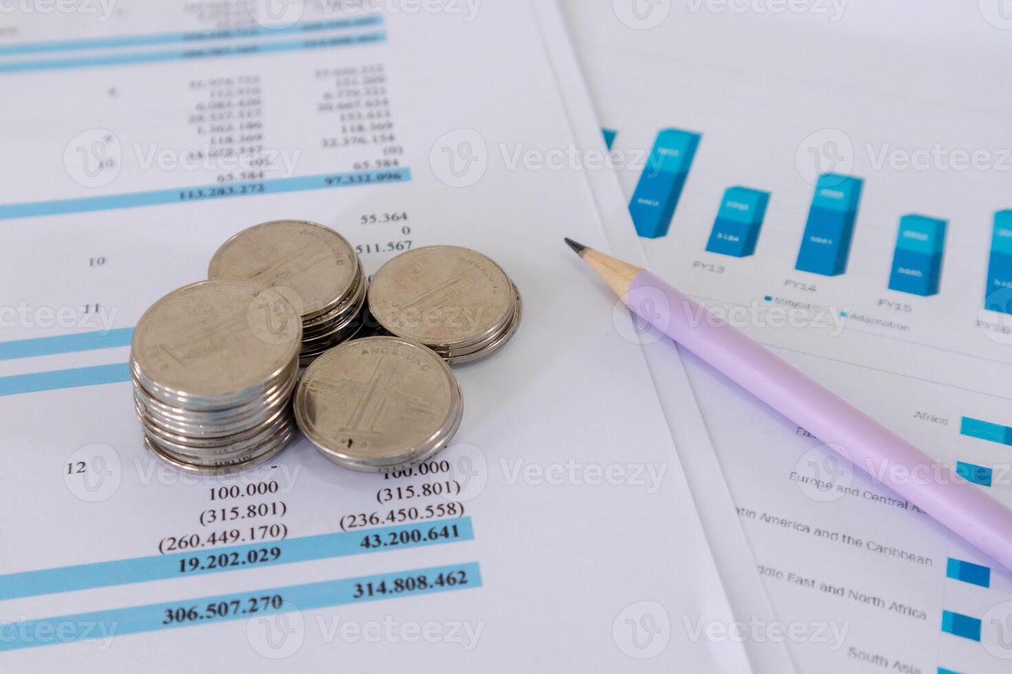 Close up view of stack of coins and pencil on top of financial data paperwork photo