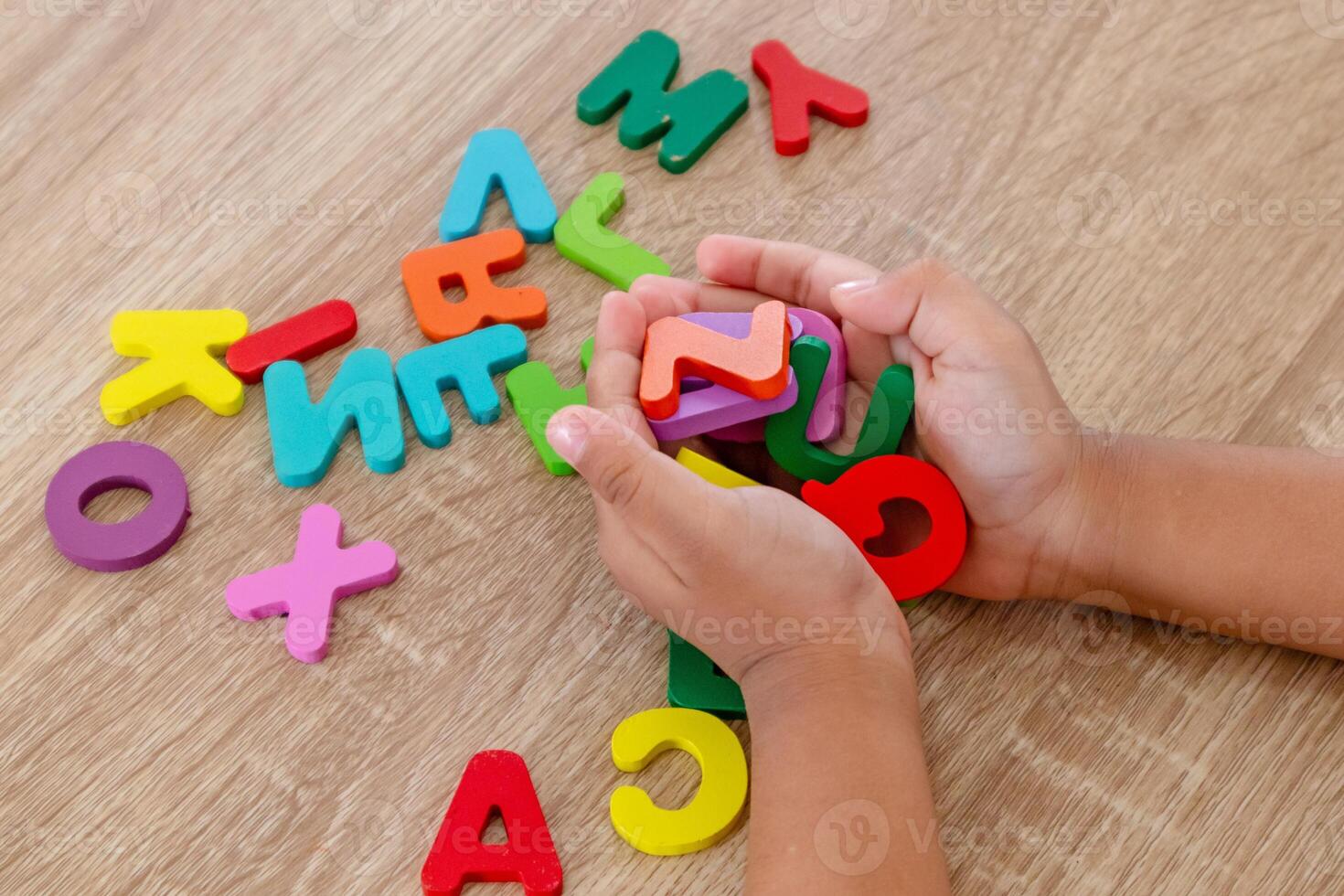 Close up view of a handful of wooden alphabet letters in the palm of a little girl's hand photo