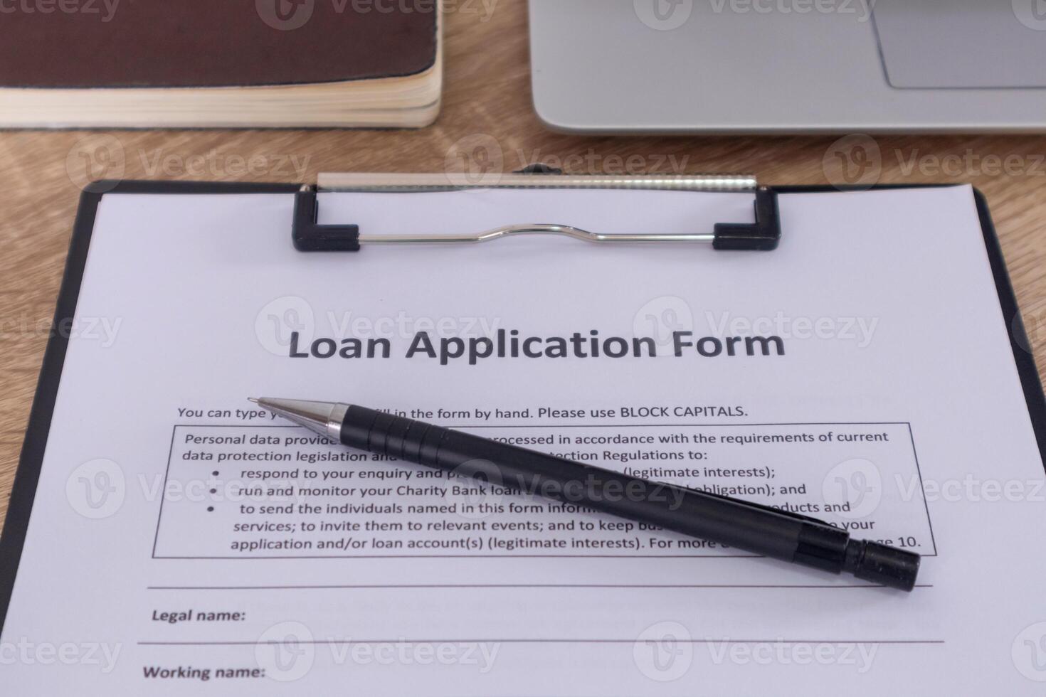 Loan application form on the wooden table with pen, laptop, and notebook. photo