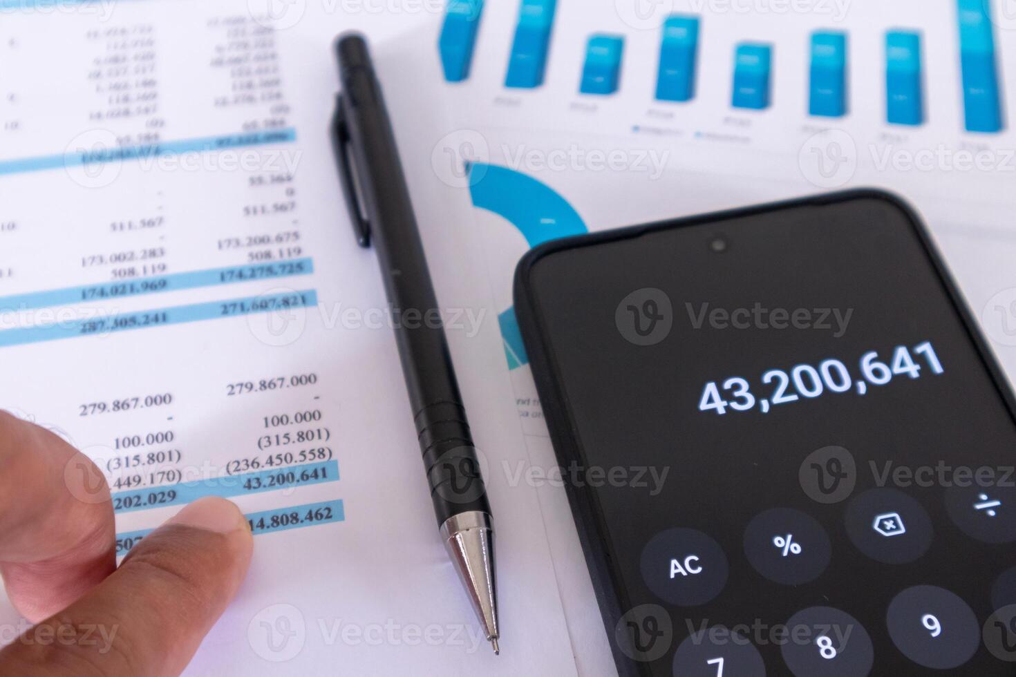 Close up view of financial data report on work paper with pen and calculator app on mobile phone. An auditor analyzes financial report data. photo