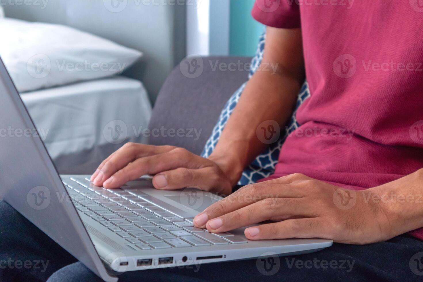 Man working on laptop in his bedroom. Working from home, working on holiday or working from anywhere concept. photo