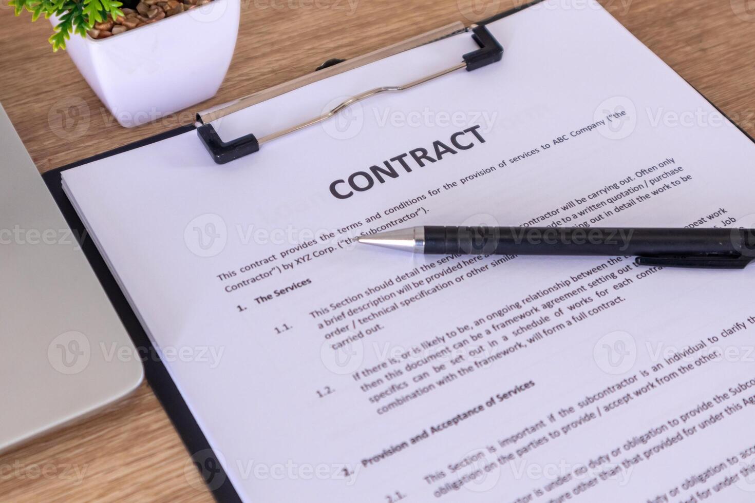 Contract documents on the wooden table with pen and laptop photo