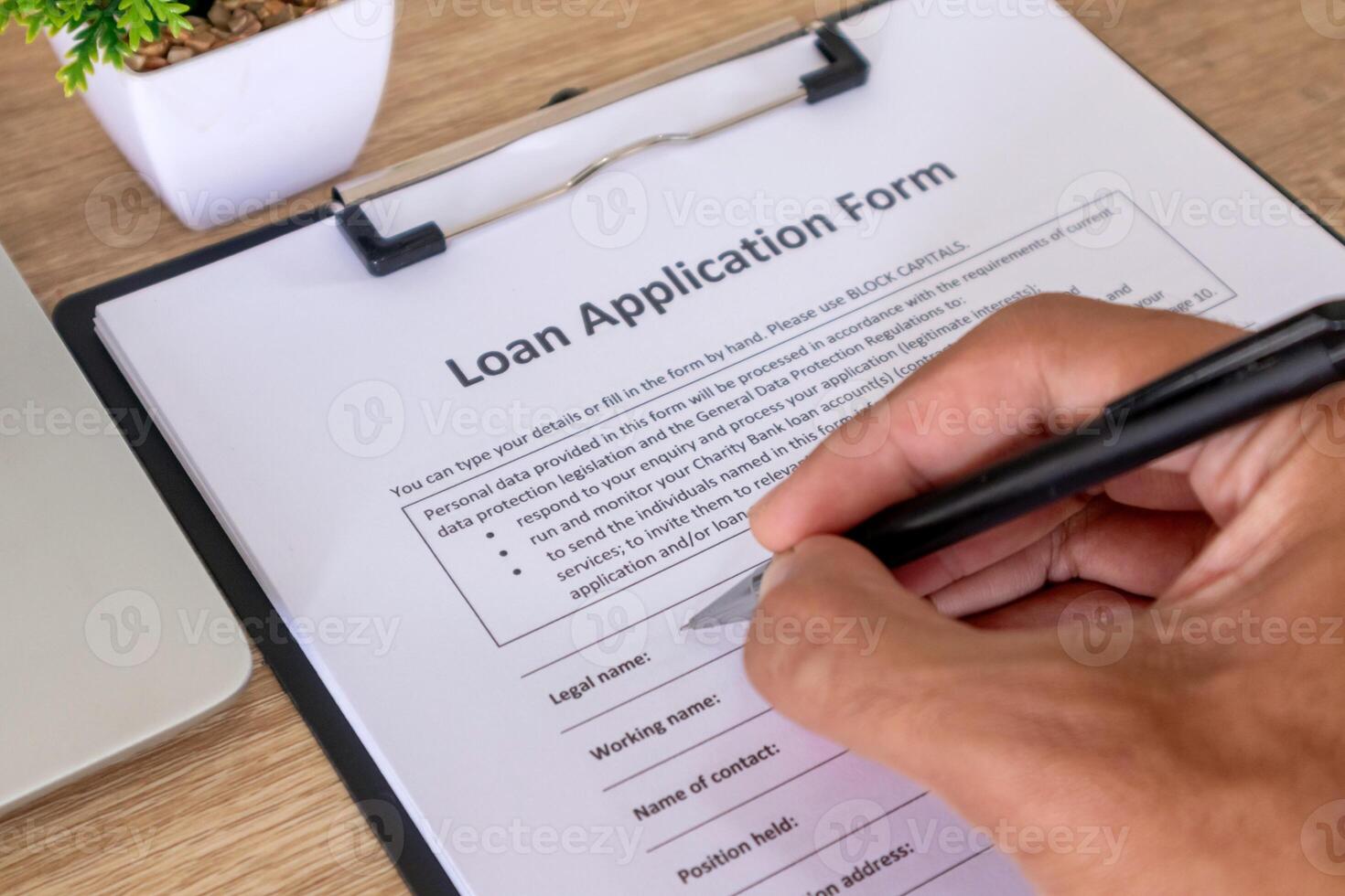 Close up view of hand holding pen to fill out loan application form photo