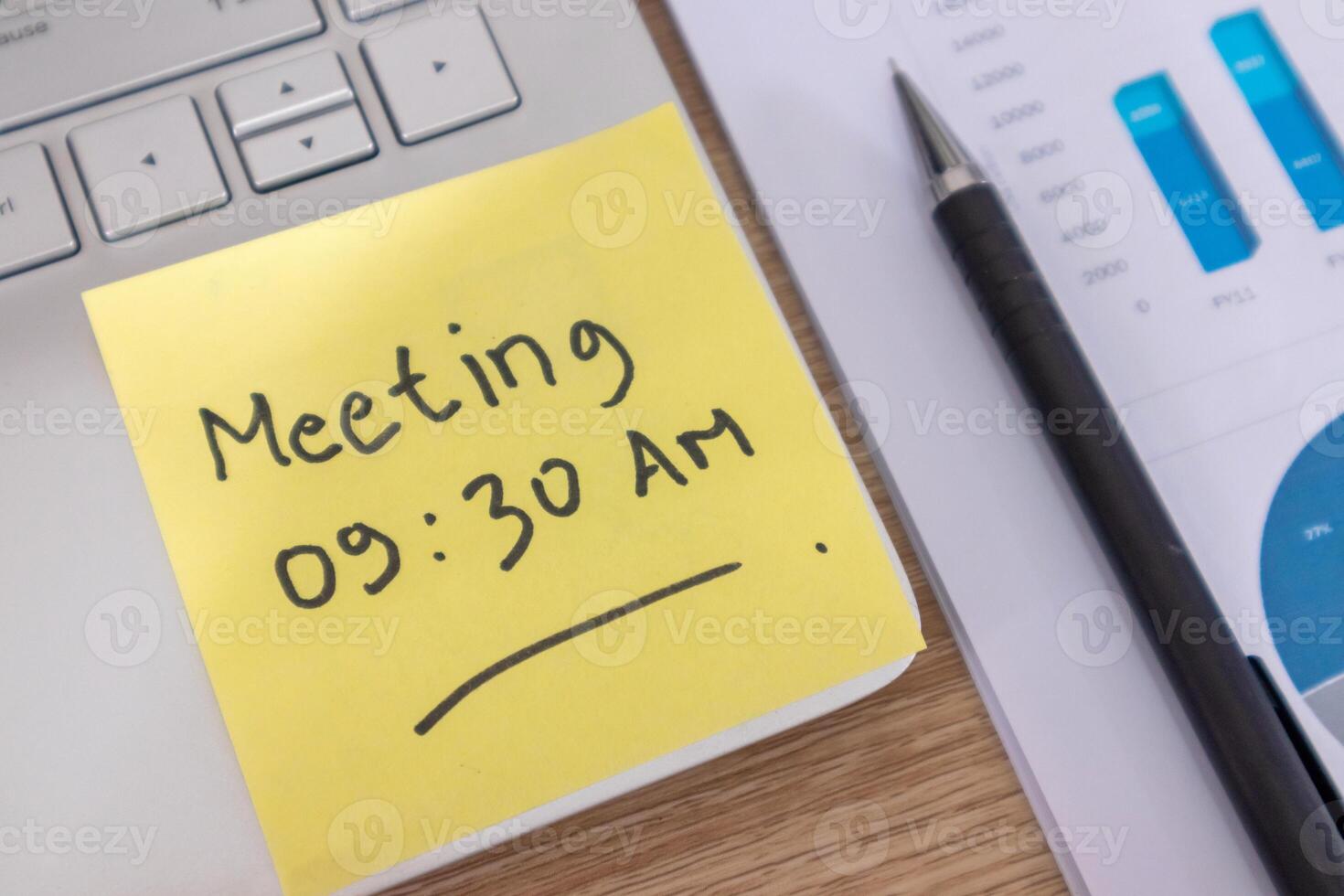 Yellow sticky note with the word Meeting 09.30 AM on a laptop. Meeting schedule concept. photo