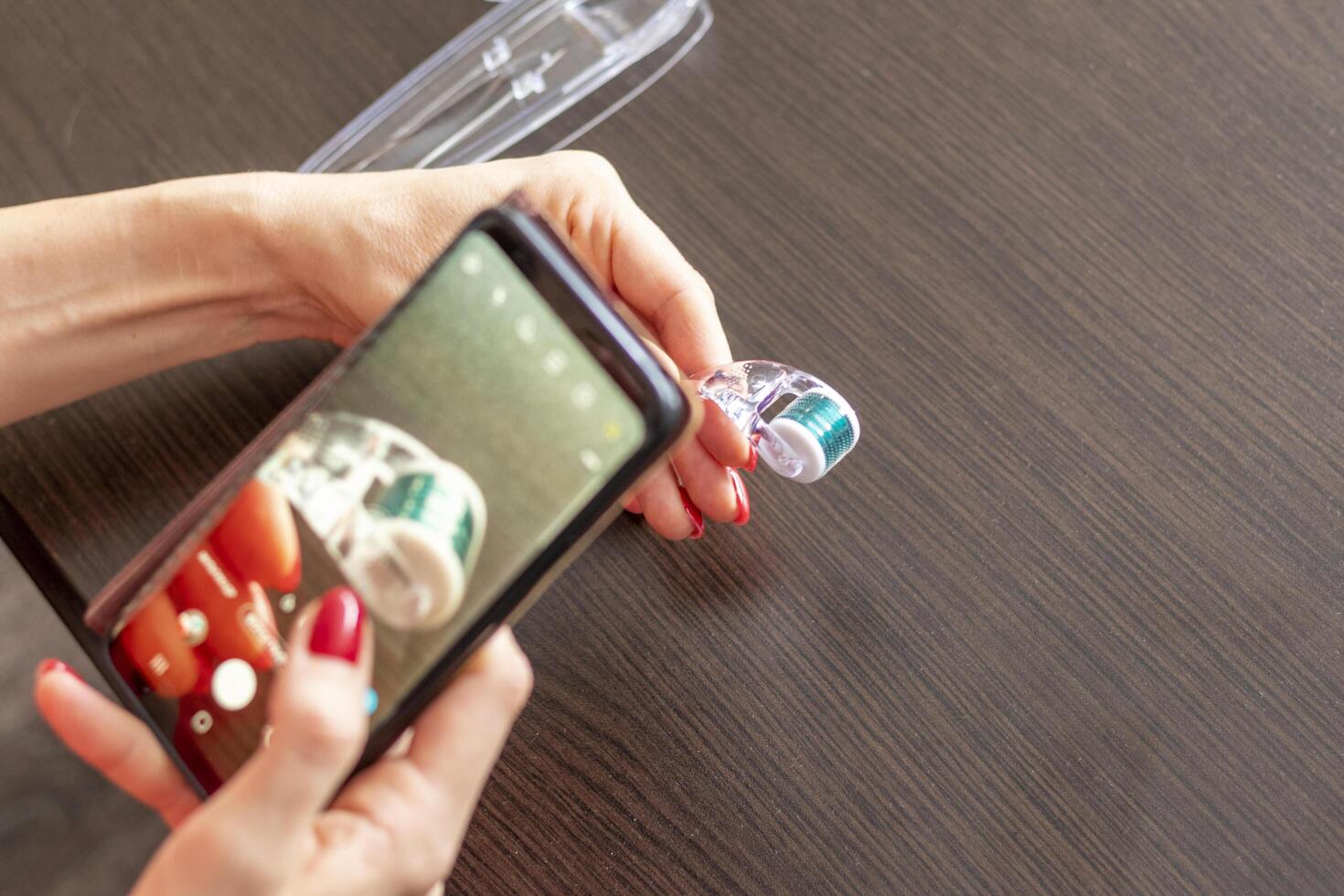Woman taking a picture of the micro needle skin care derma roller. Concept photo