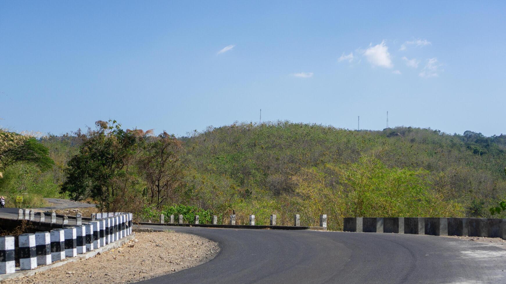 road with views of green hills and blue skies photo