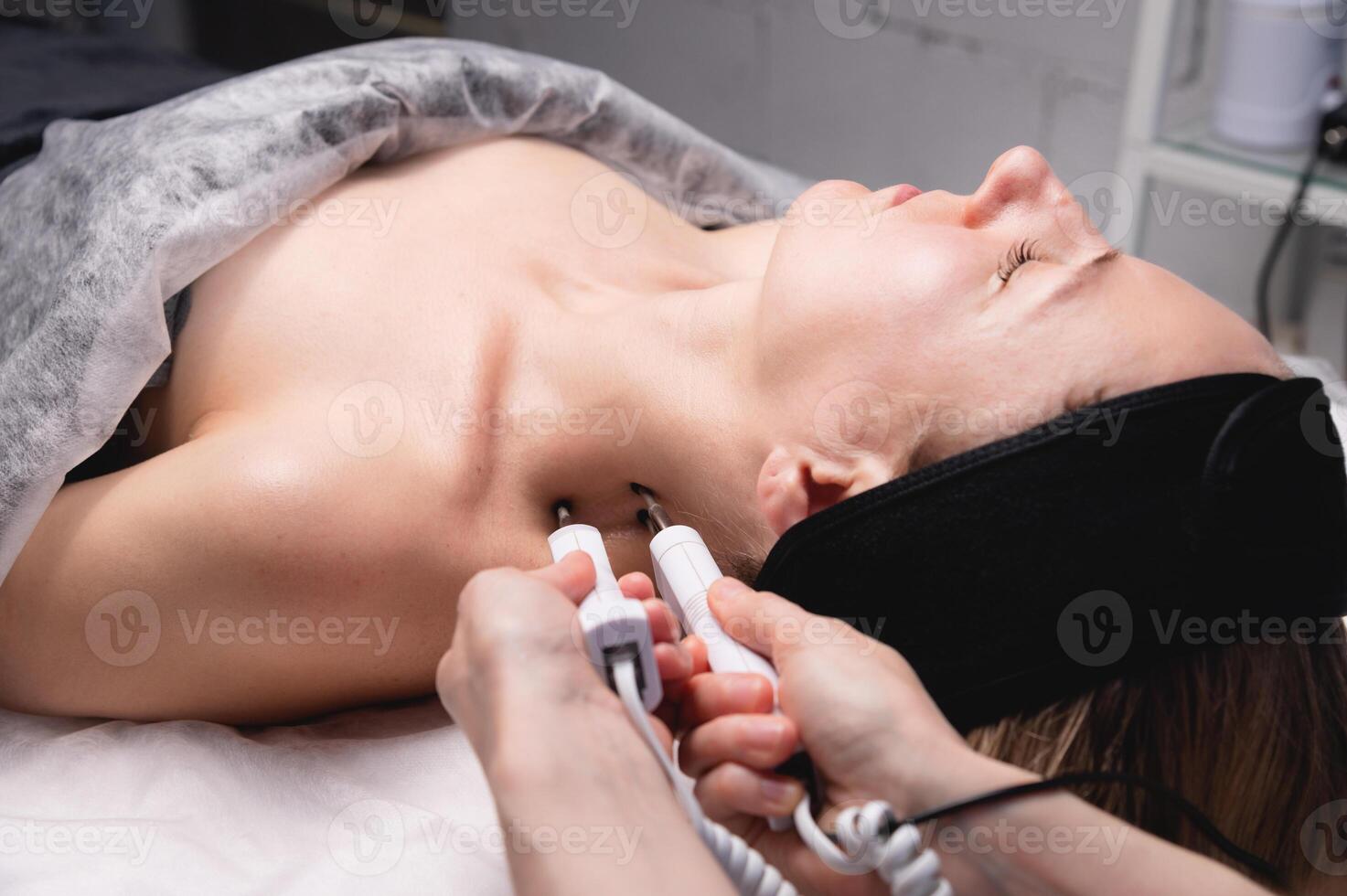 Ultrasonic facial treatment on ultrasound face machine. Woman taking electric lift massage spa salon. Stimulation muscles on professional equipment microcurrent therapy. New methods of rejuvenation photo