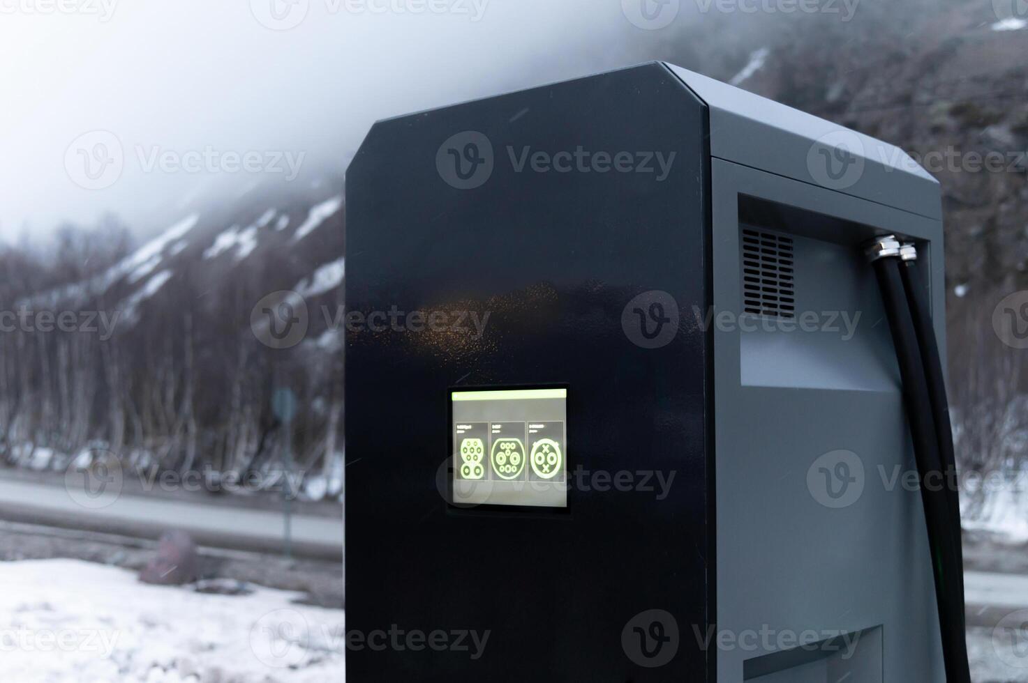 Close-up Electric car charging station, row of gas stations stands against the backdrop of mountains in fog in winter, cloudy weather photo