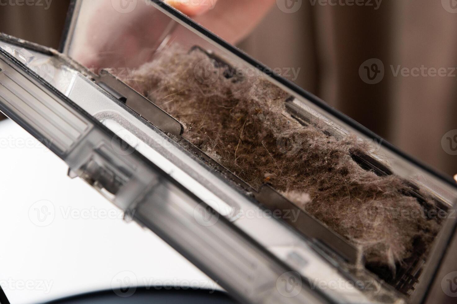 Maintenance of a smart robot vacuum cleaner. Women's hands maintain and clean a round robot vacuum cleaner. Organization of uninterrupted operation of a home cleaner photo