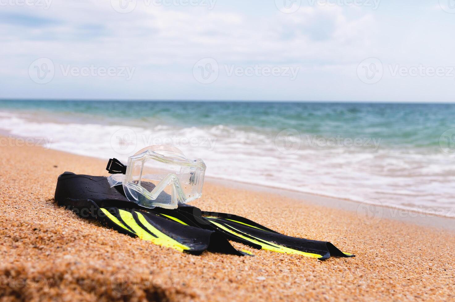 On the golden sea beach lie a snorkel mask and fins. Concept of snorkeling at sea photo