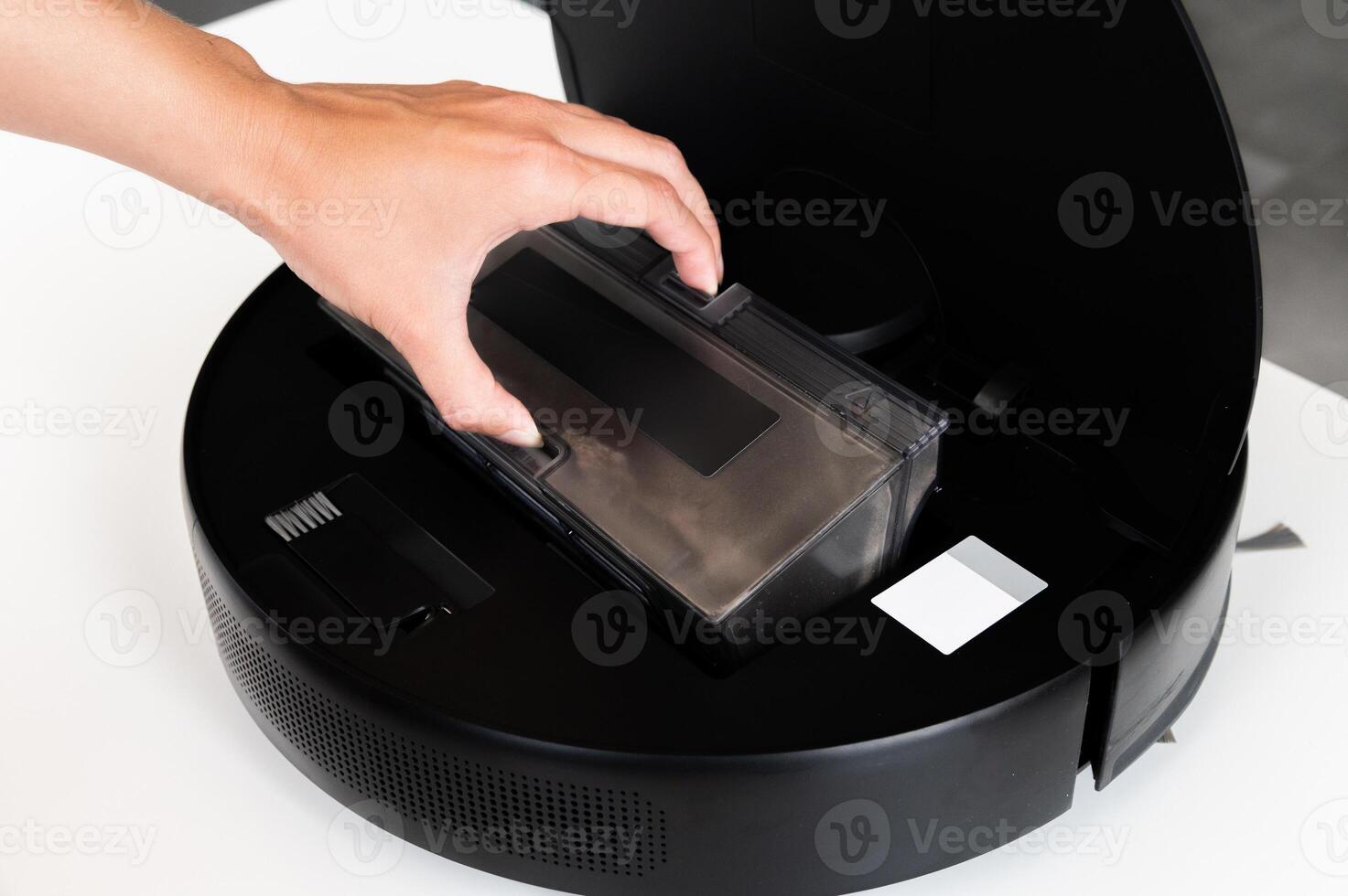 container with dust from a robot vacuum cleaner in hands against the background of a vacuum cleaner photo