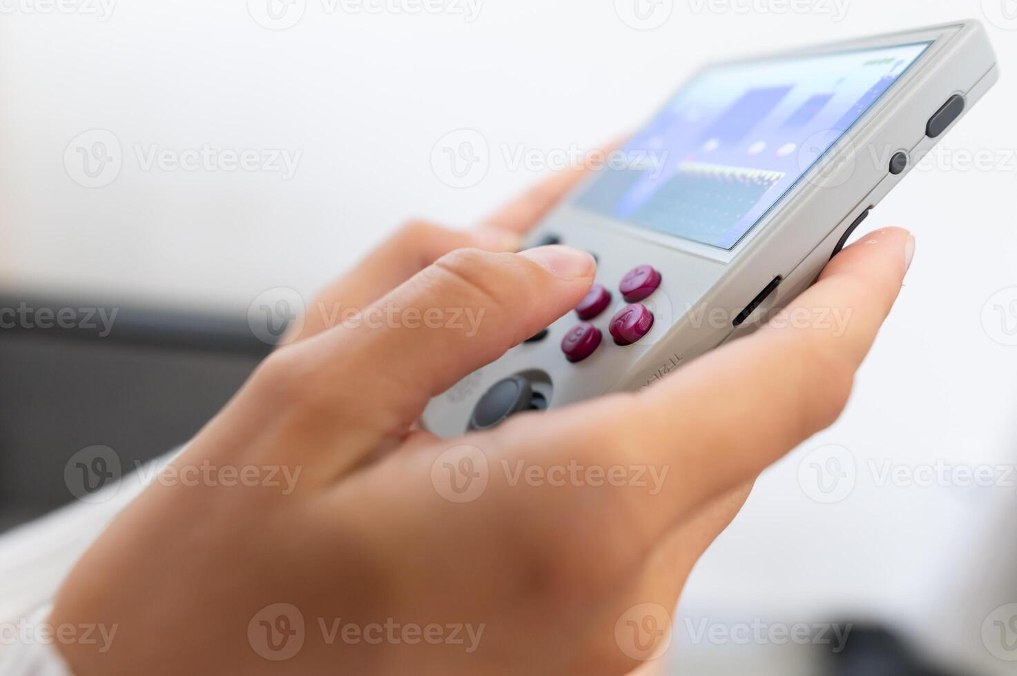 Close-up of female hands of young Caucasian woman holding retro game console. Girl playing retro games on portable game console. Shallow depth of field. Selective focus photo