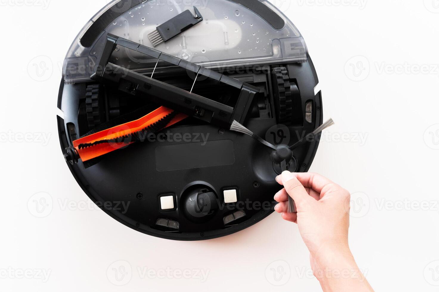Robot vacuum cleaner on white table indoors, lies upside down with wheels. Assembling new robot vacuum cleaner, round black home assistant photo