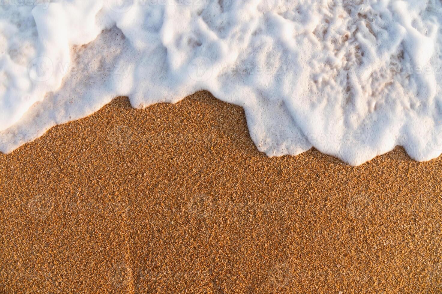 Golden sand with foam rolling in from the surf. Blank for text or advertising. Mockup photo
