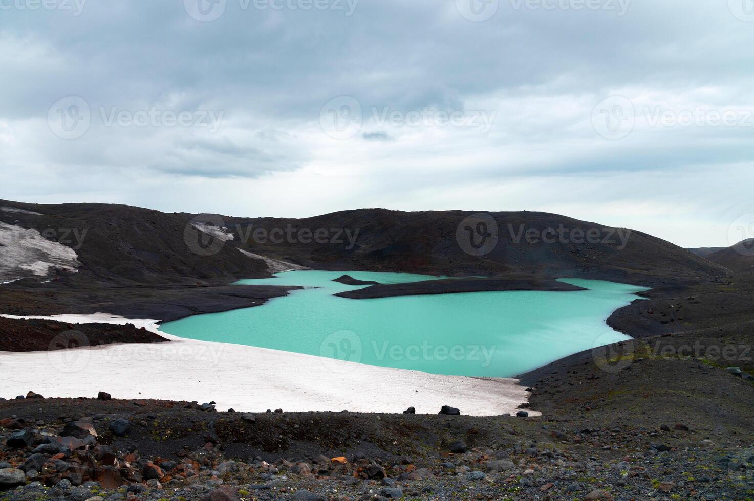 A turquoise lake surrounded by volcanic rocks and a melting glacier. Global warming and lifeless places on the planet photo