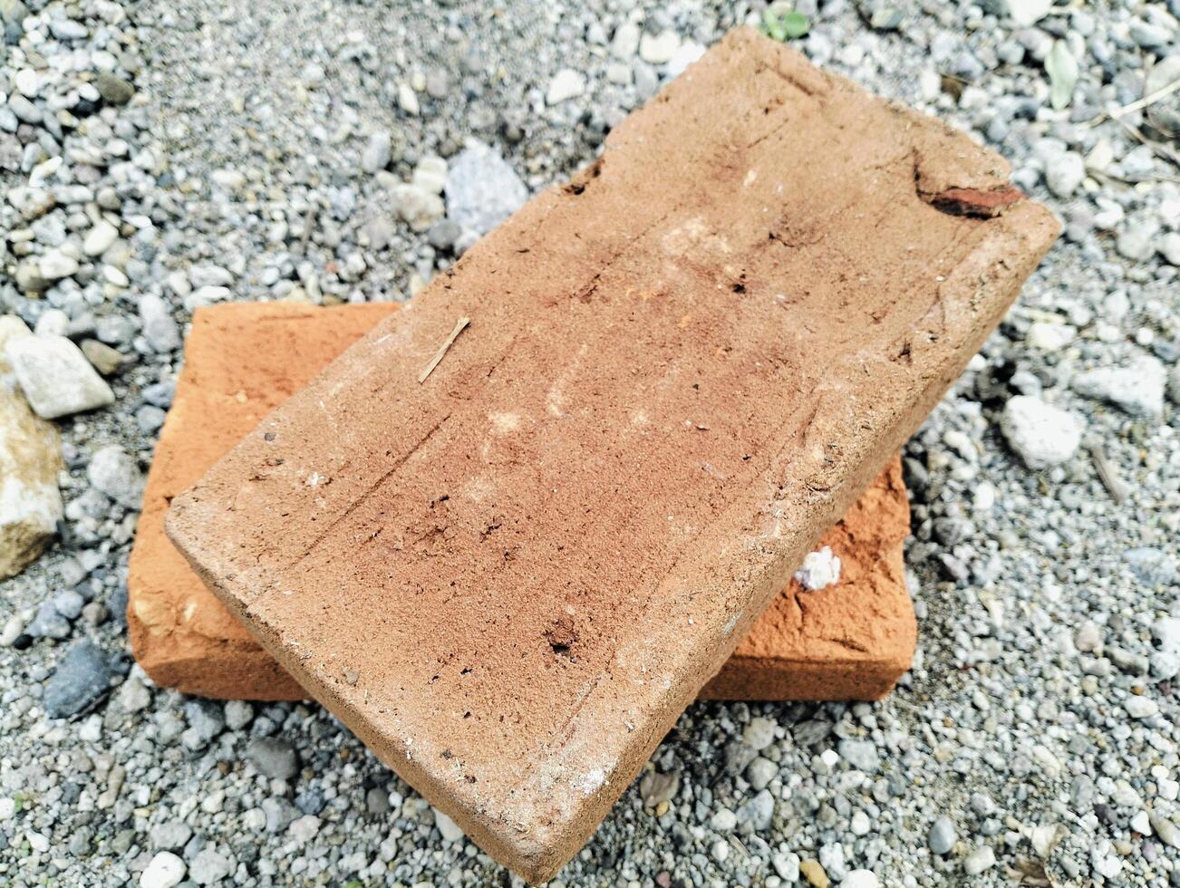 Rustic Clay Bricks Lying on Pebble Ground in Outdoor Setting photo