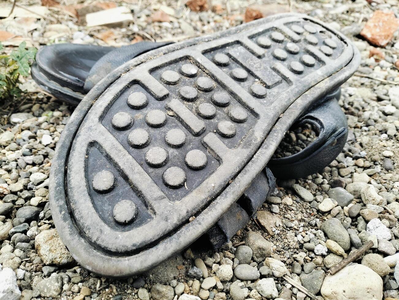 A Pair of Worn Sandals Resting on a Rocky Ground photo