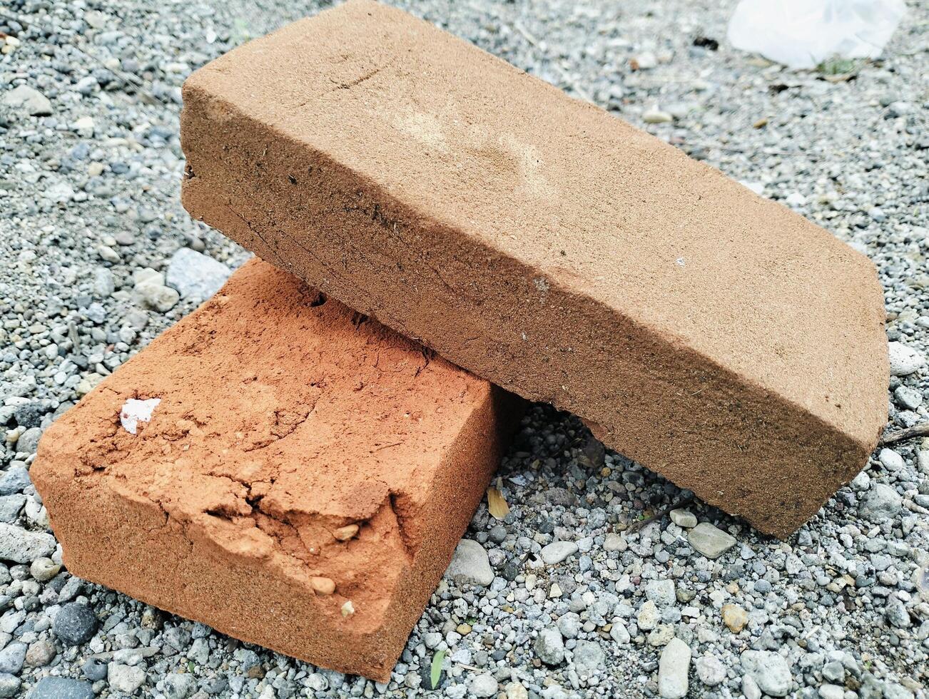 Close-Up of Weathered Clay Bricks Resting on Gravel Surface photo