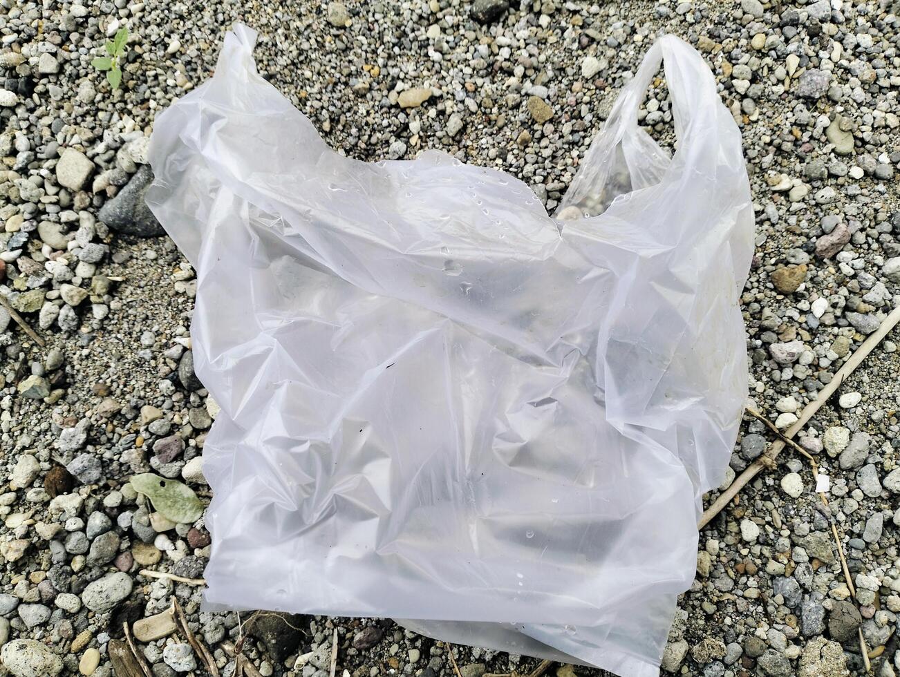 White plastic bag lying on sandstone, Used white plastic bags, plastic trash photo