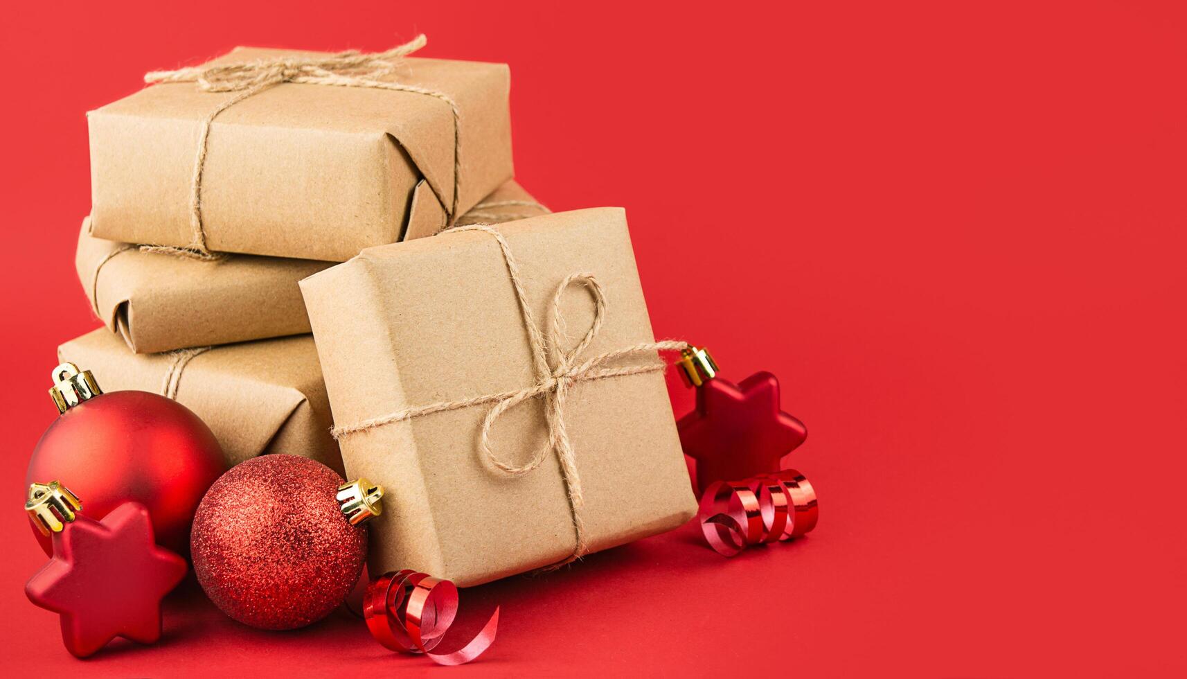 Christmas composition of gifts on a red background. Festive New Year's decorations. Christmas background. Layout of a banner, postcard. Side view. Copy space. Banner. photo