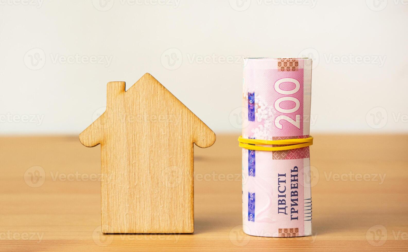 The concept of paying utility bills. Ukrainian bills of 200 hryvnias and a wooden house. Side view. photo
