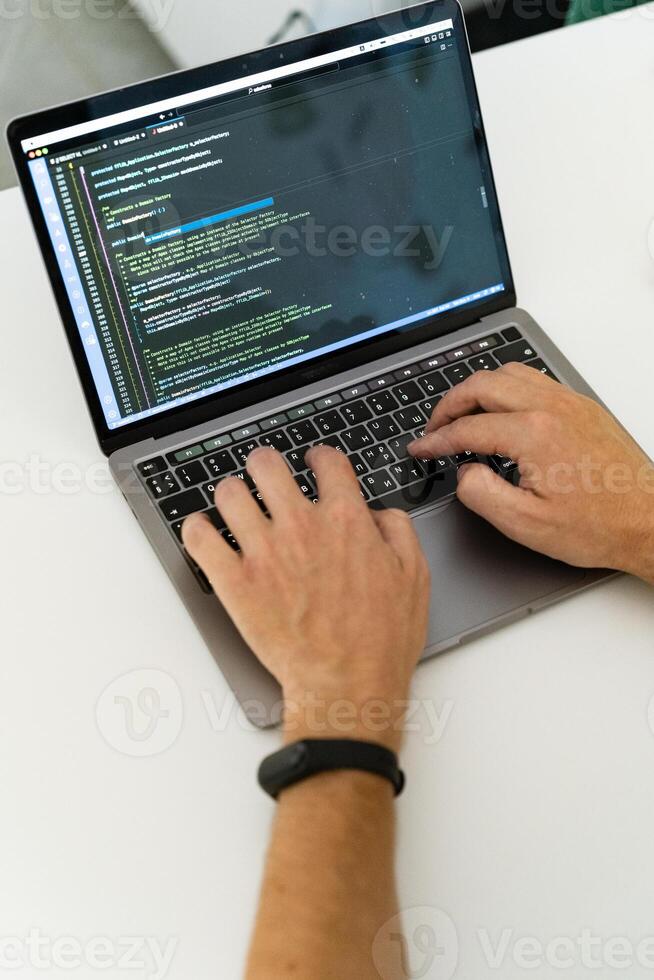 Programmer, typing with two hands, one of which is wearing a watch. photo