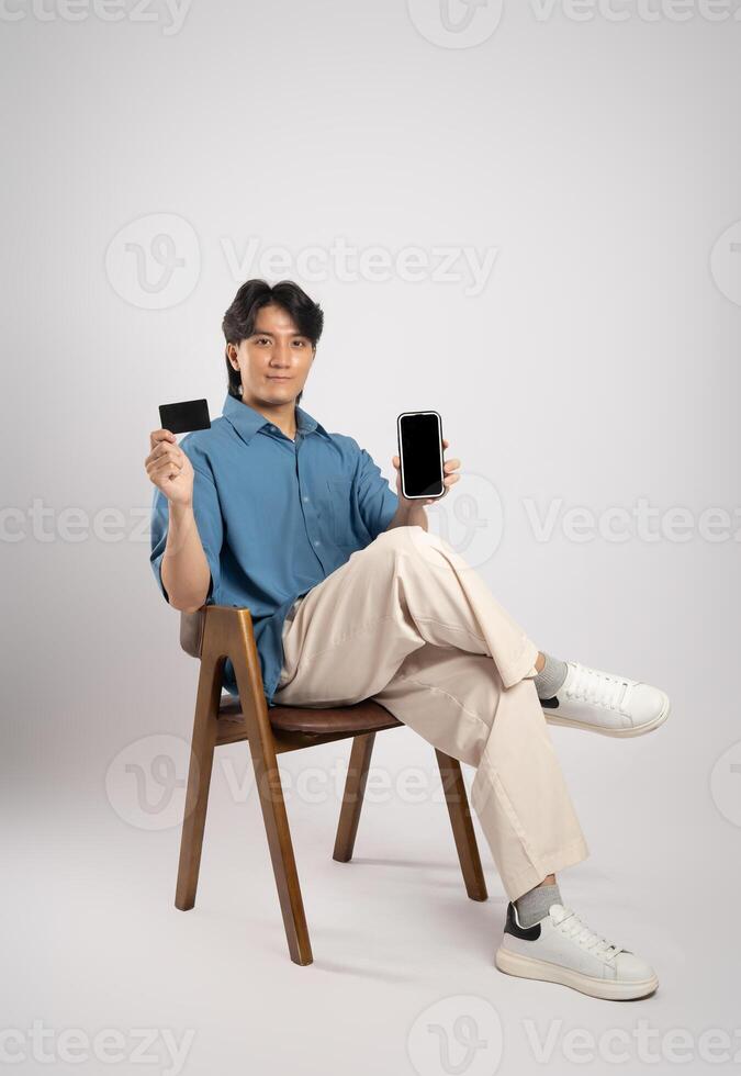 Portrait of young Asian business man sitting in chair, isolated on white background photo