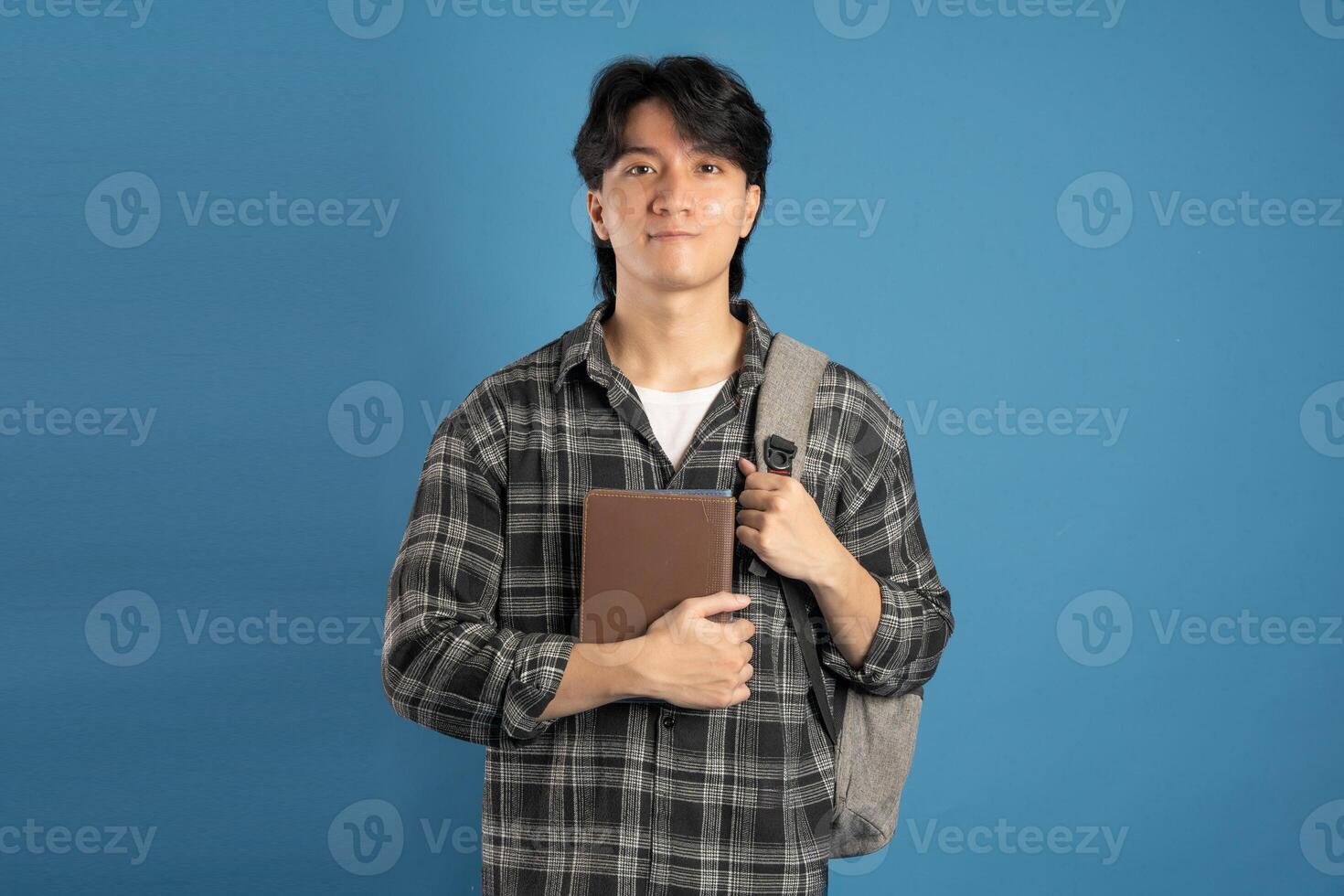 Portrait of Asian male student posing on blue background photo
