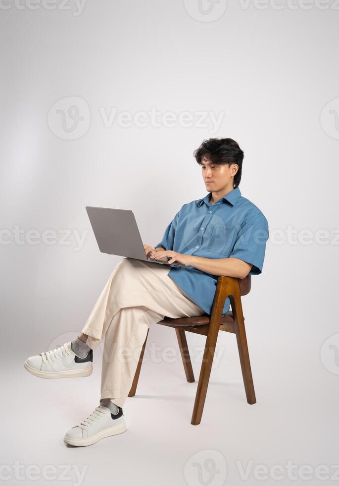Portrait of young Asian business man sitting in chair, isolated on white background photo