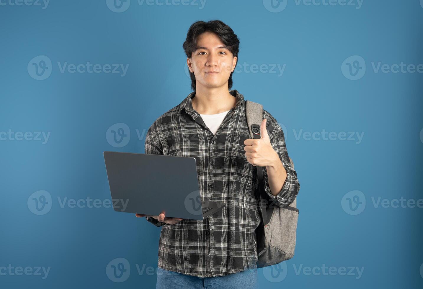 Portrait of Asian male student posing on blue background photo