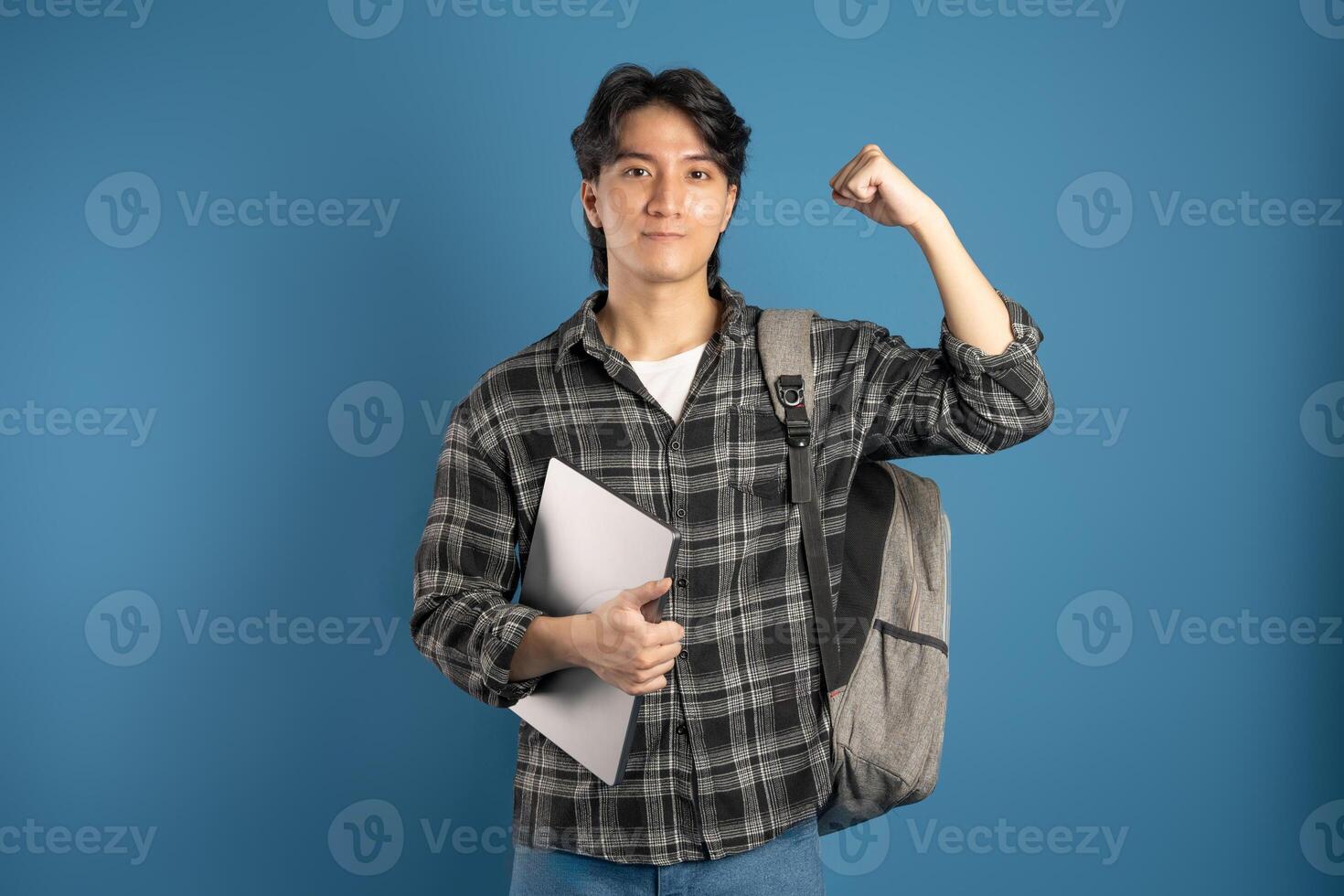 Portrait of Asian male student posing on blue background photo