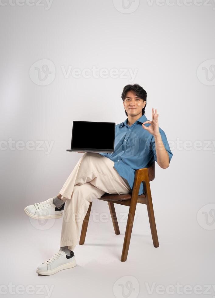 Portrait of young Asian business man sitting in chair, isolated on white background photo