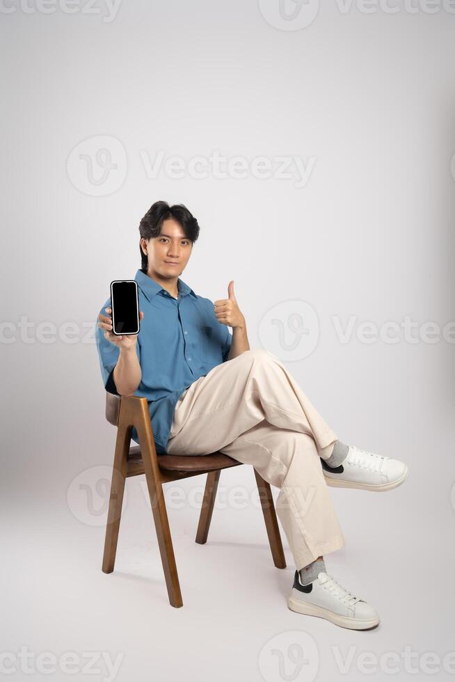 Portrait of young Asian business man sitting in chair, isolated on white background photo
