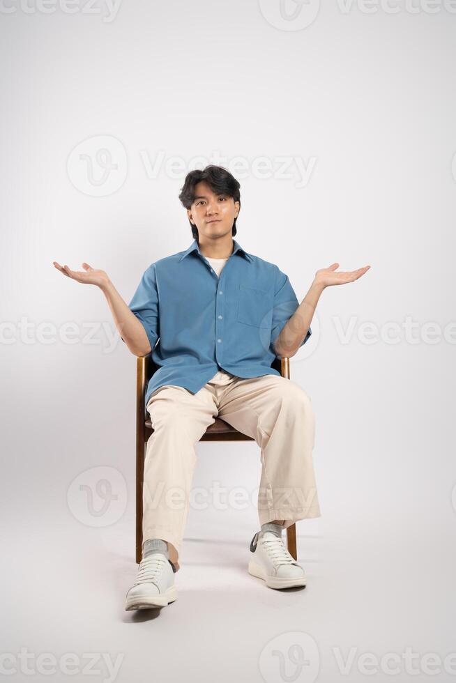 Portrait of young Asian business man sitting in chair, isolated on white background photo
