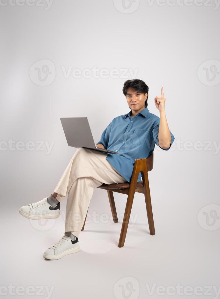 Portrait of young Asian business man sitting in chair, isolated on white background photo