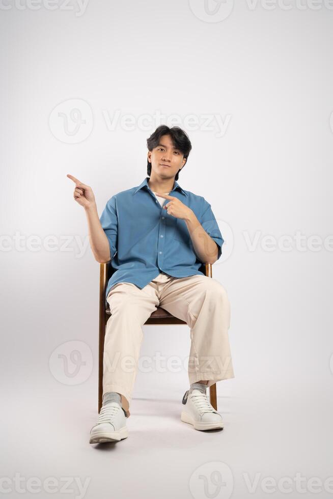 Portrait of young Asian business man sitting in chair, isolated on white background photo