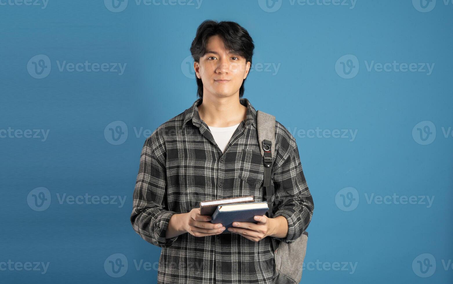 Portrait of Asian male student posing on blue background photo
