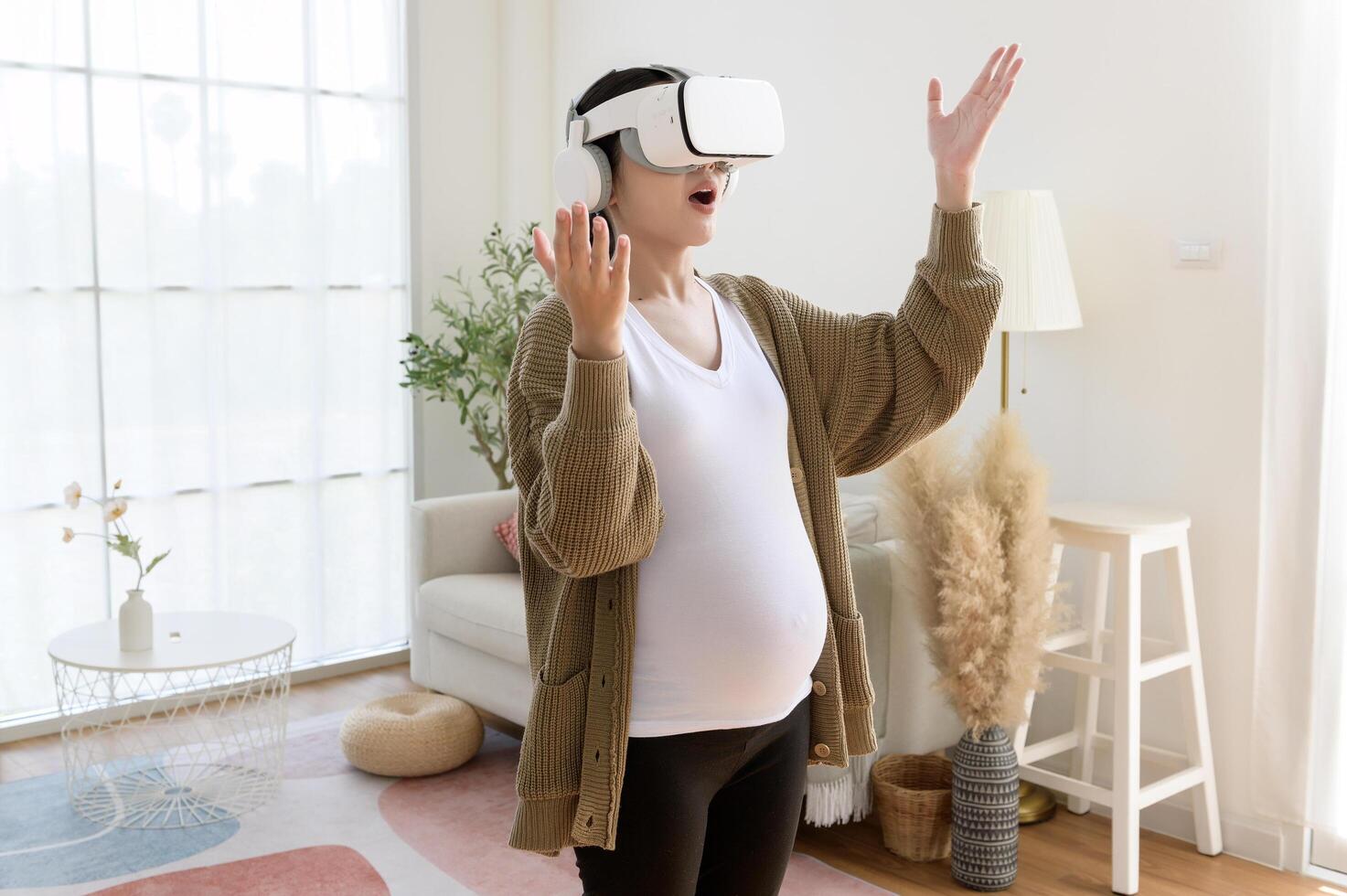 Pregnant woman wearing vr box using future technology for entertainment in living room photo