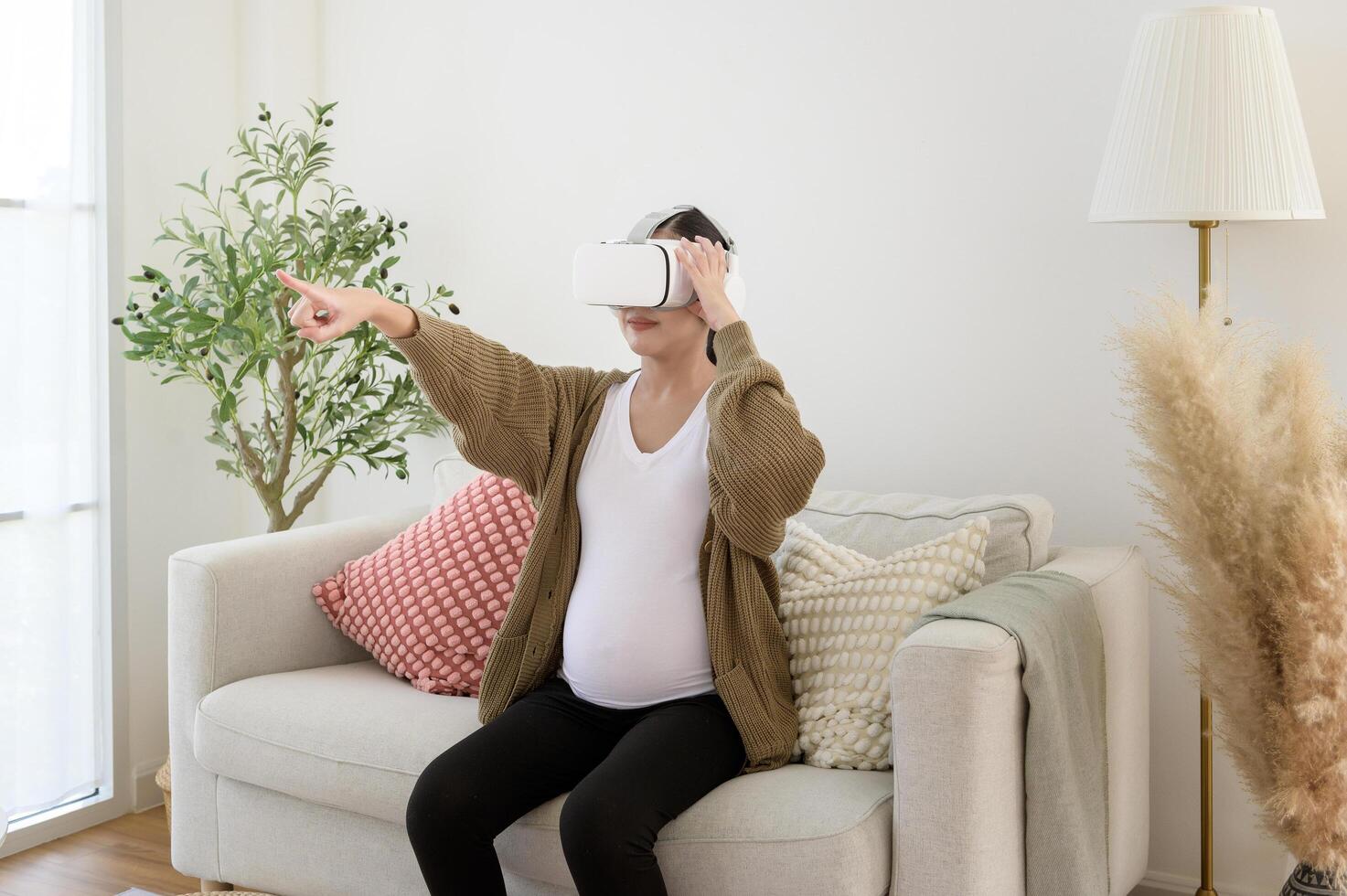 Pregnant woman wearing vr box using future technology for entertainment in living room photo