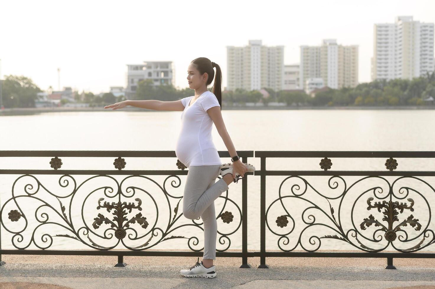 Beautiful pregnant woman stretching and exercising in the park photo