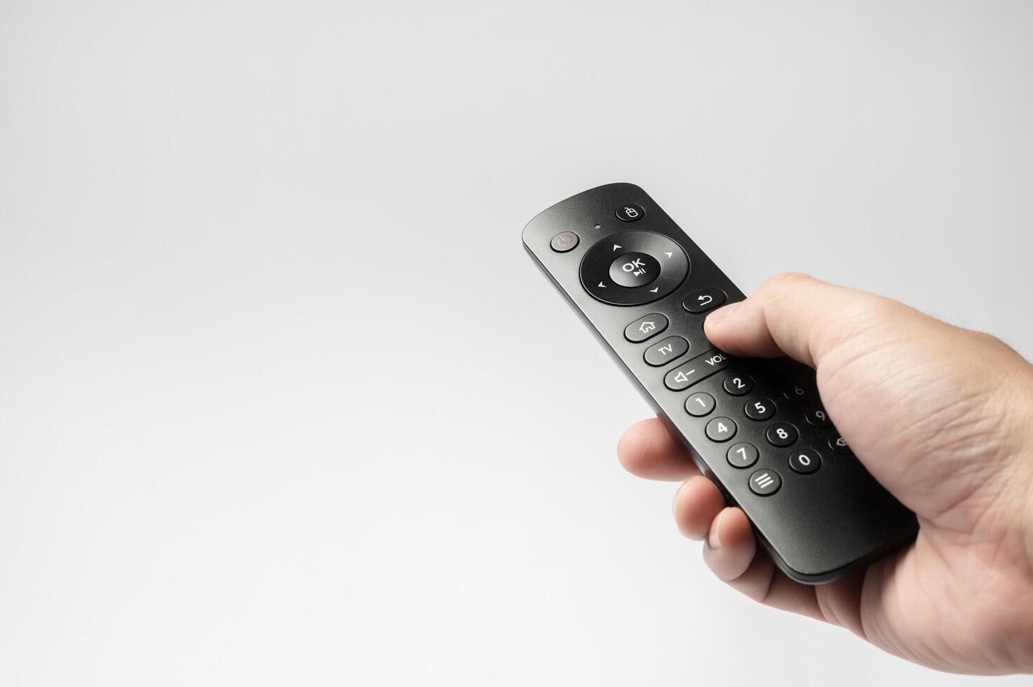 Human hand using TV remote control over white background photo