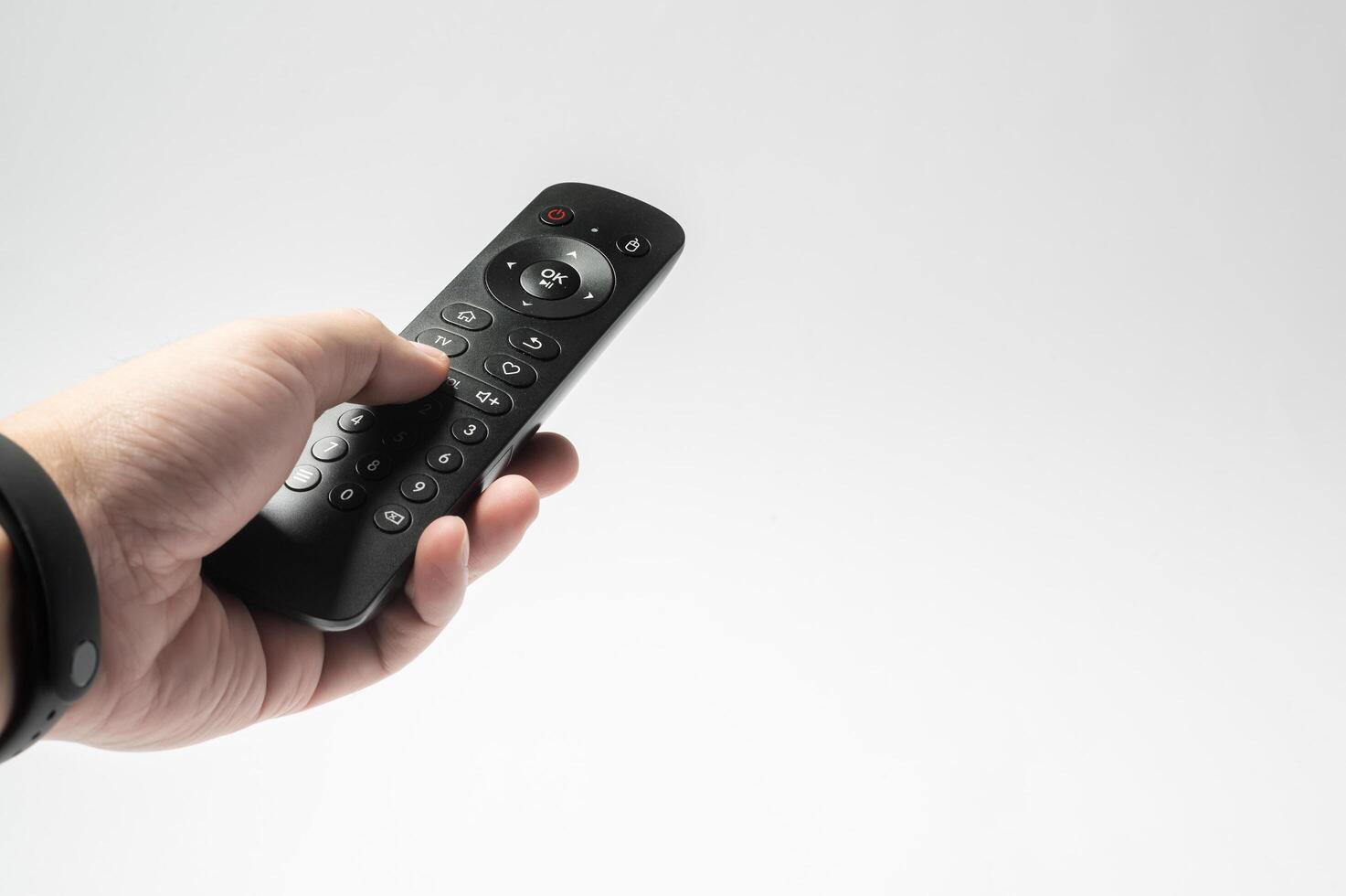 Human hand using TV remote control over white background photo