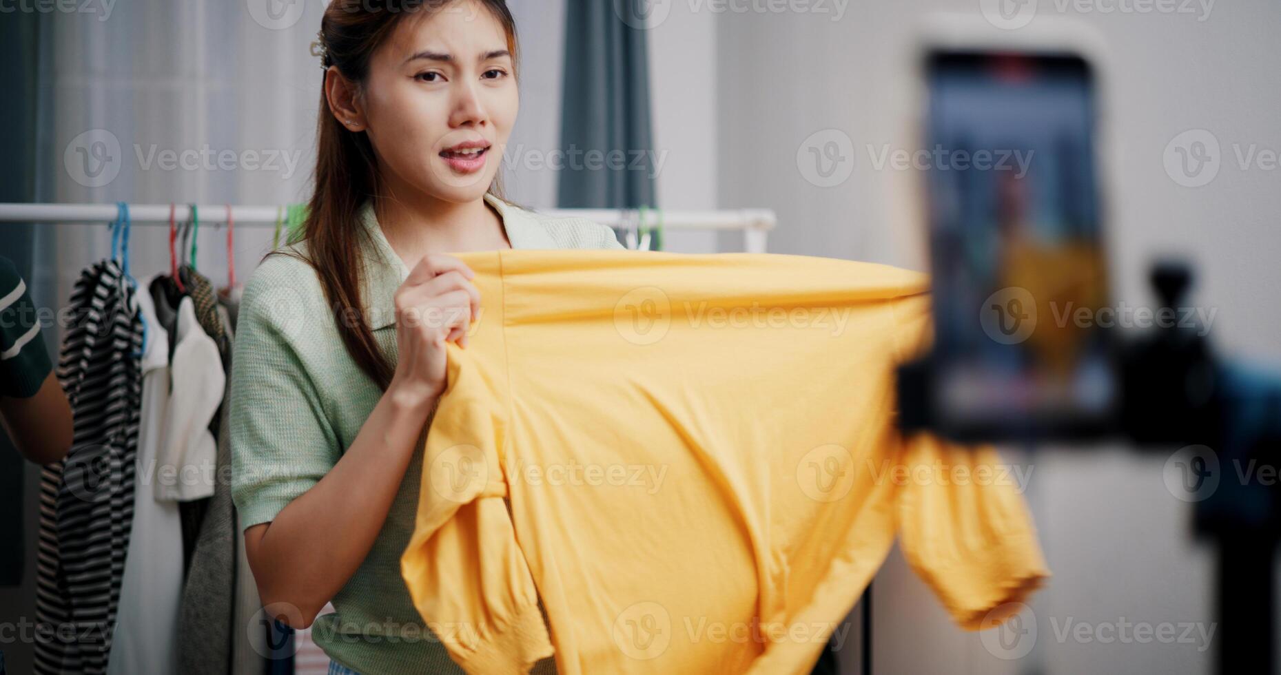 Selective focus, Two cheerful woman influencers are live streaming sell clothes on social media or blogging in home studio. Remote buying, Online shopping. photo