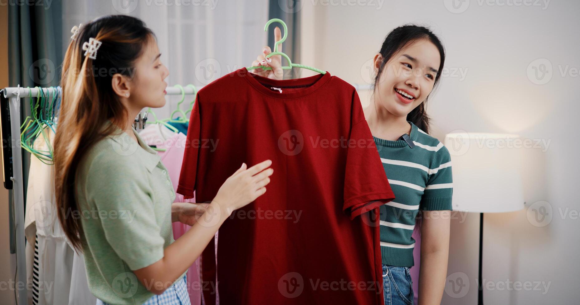 Portrait of Two cheerful woman influencers are live streaming to promote a clothing sell during a flash sale on social media or blog in a home studio. Remote shopping, online shopping. photo