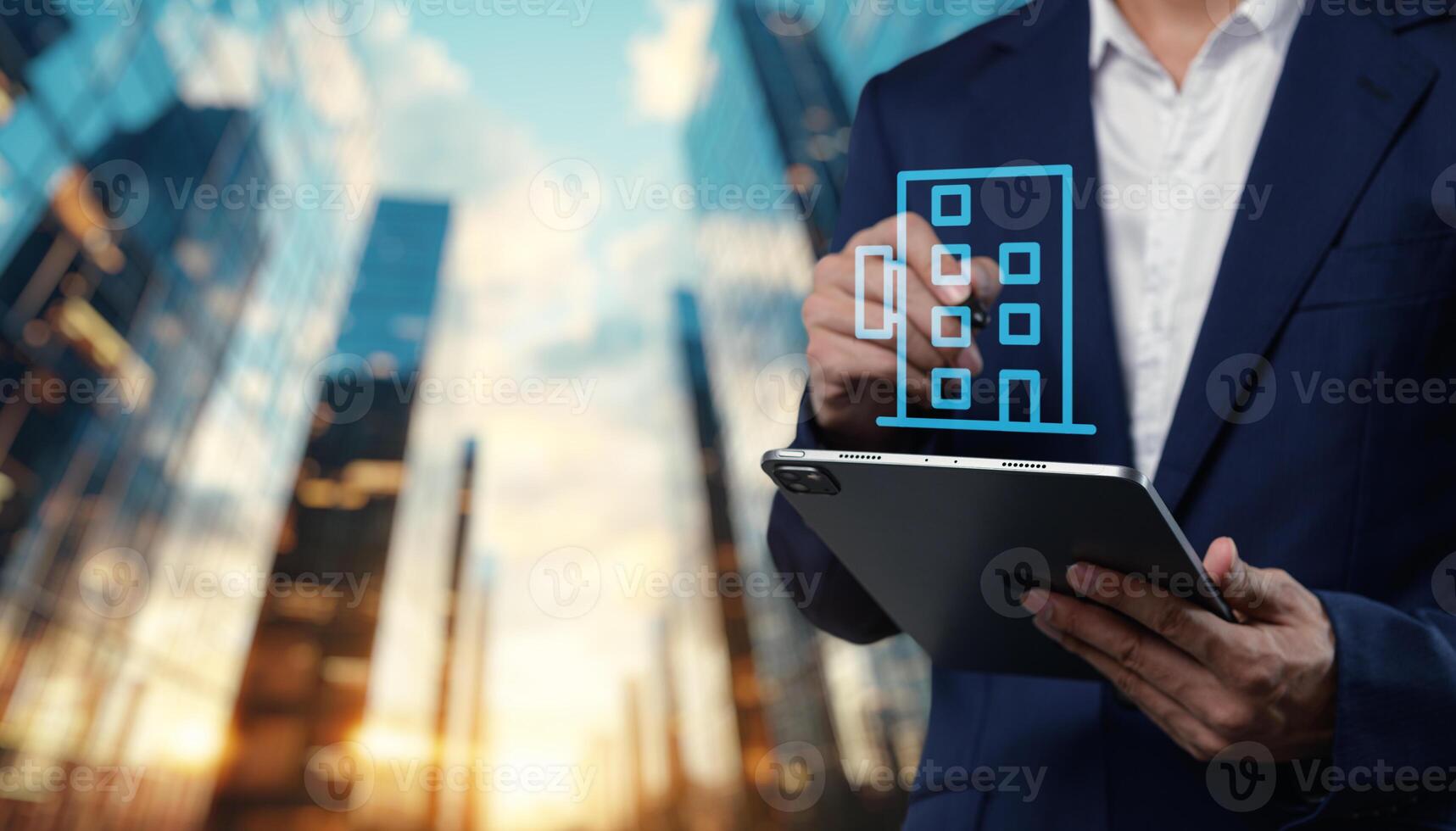 Businessman holding tablet with building icon on city background photo