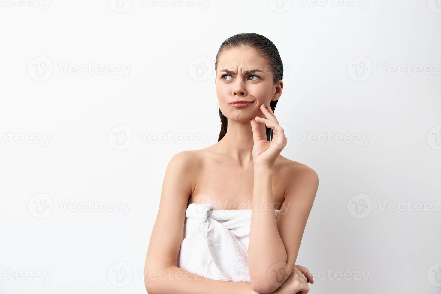 thoughtful woman with a questioning expression, wearing a towel, against a minimalistic white photo