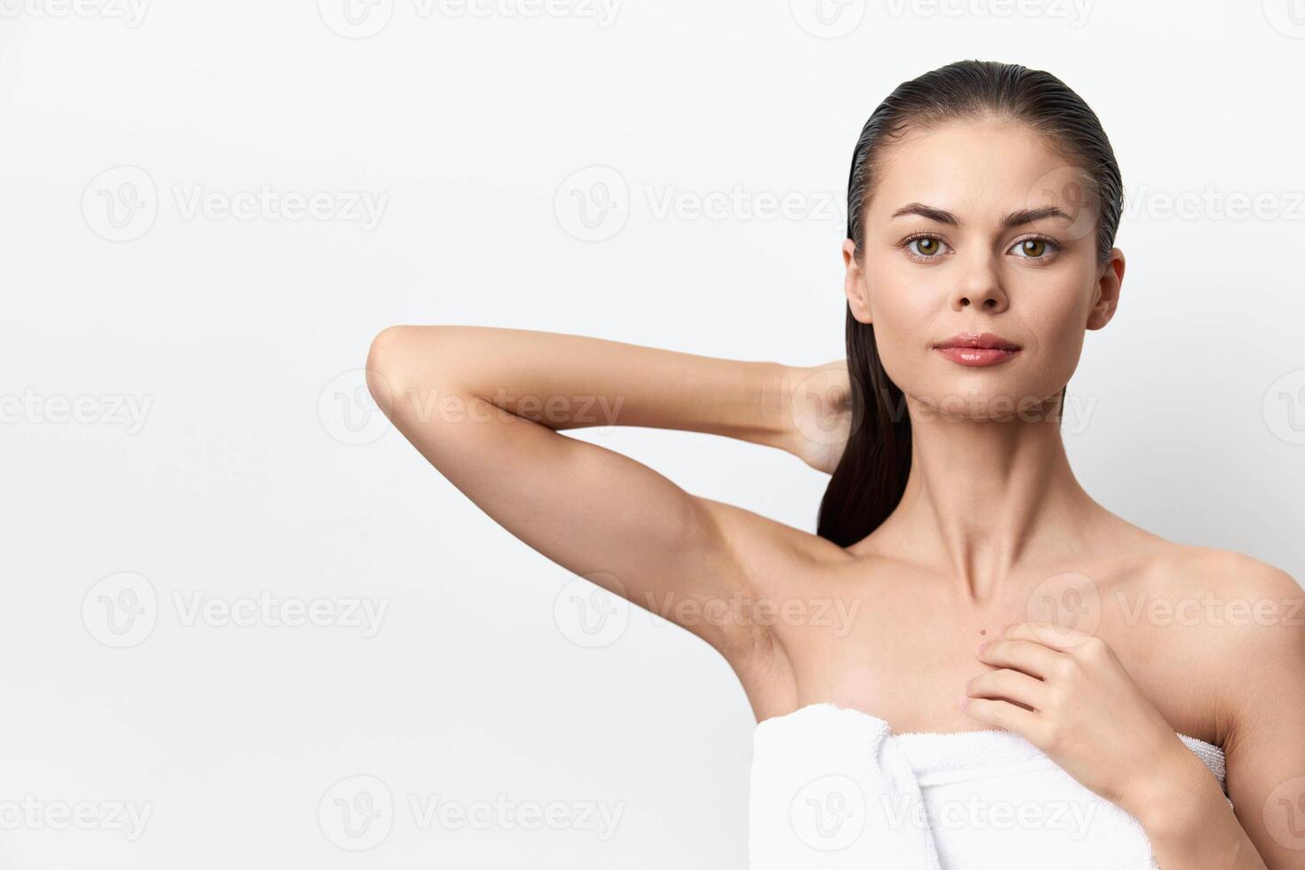 young woman with flawless skin standing against a plain white background, exuding confidence and photo